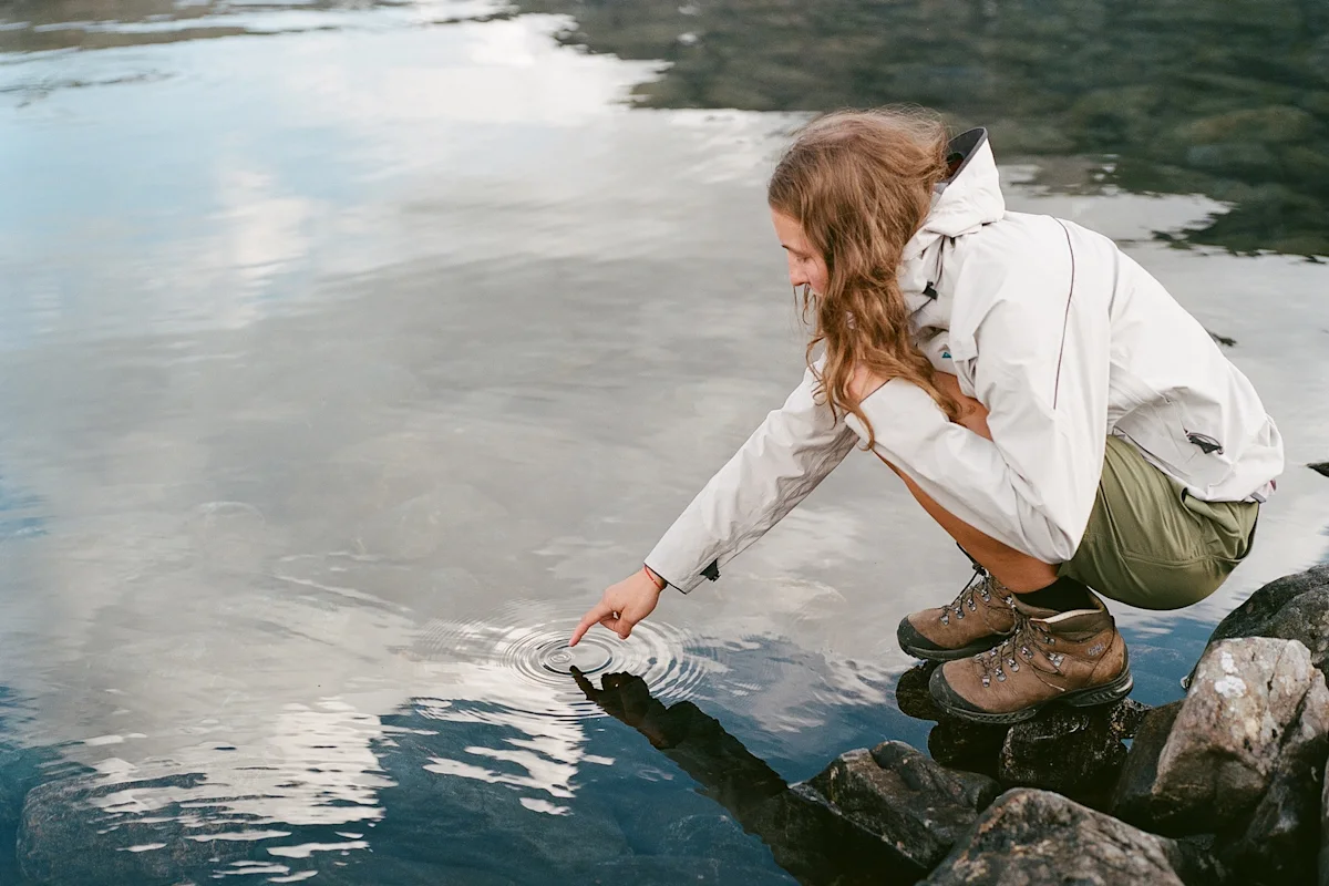 A hiker testing the water depth of a mountain stream before crossing.
