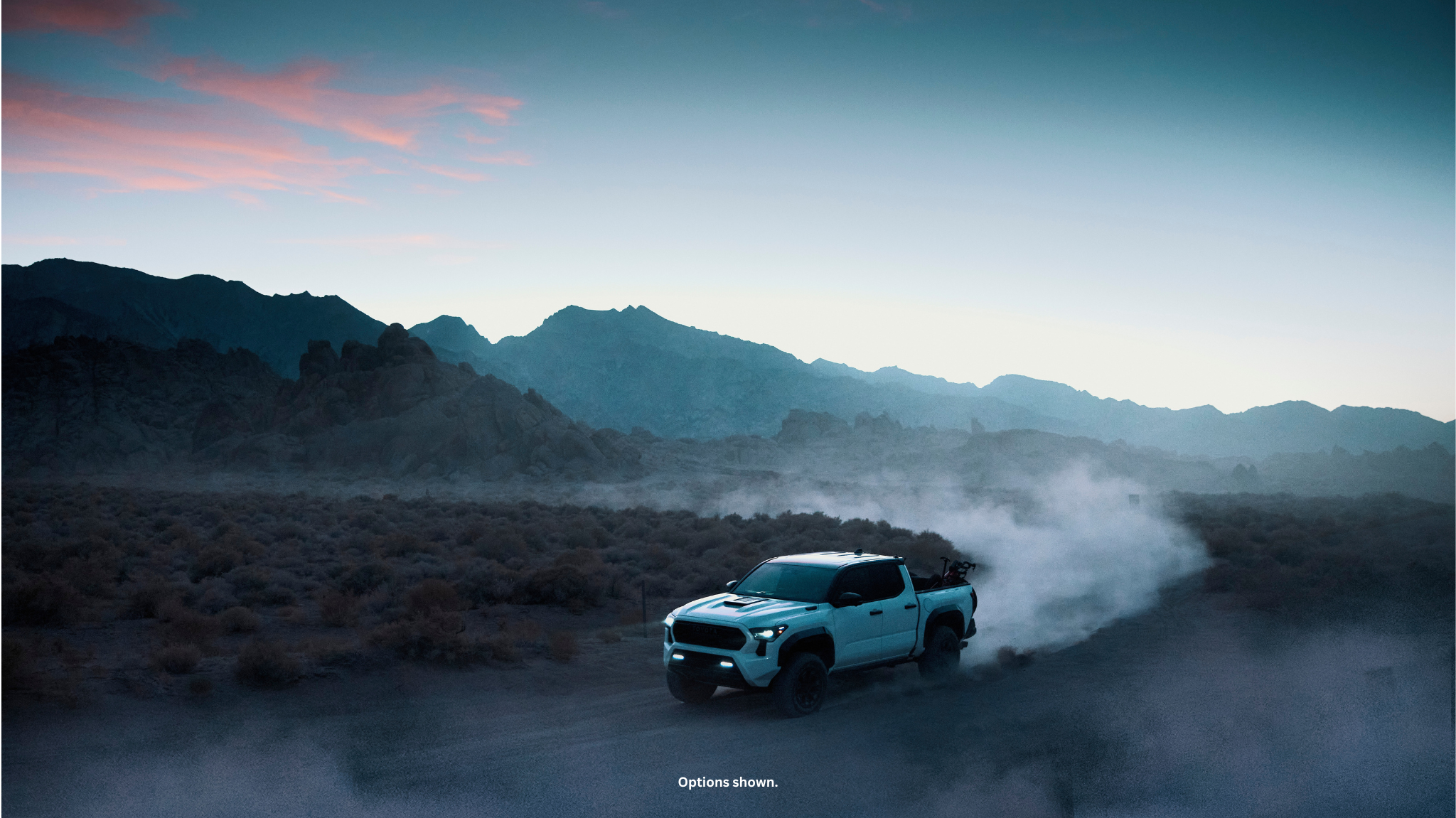A Toyota Tacoma with specialized off-road suspension on a mountain trail.