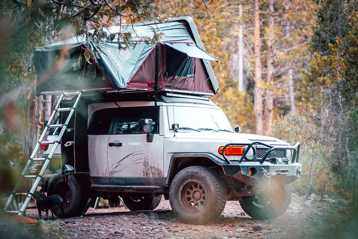 An iKamper Skycamp 2.0 hardshell rooftop tent mounted on a Toyota FJ Cruiser in a rugged environment.
