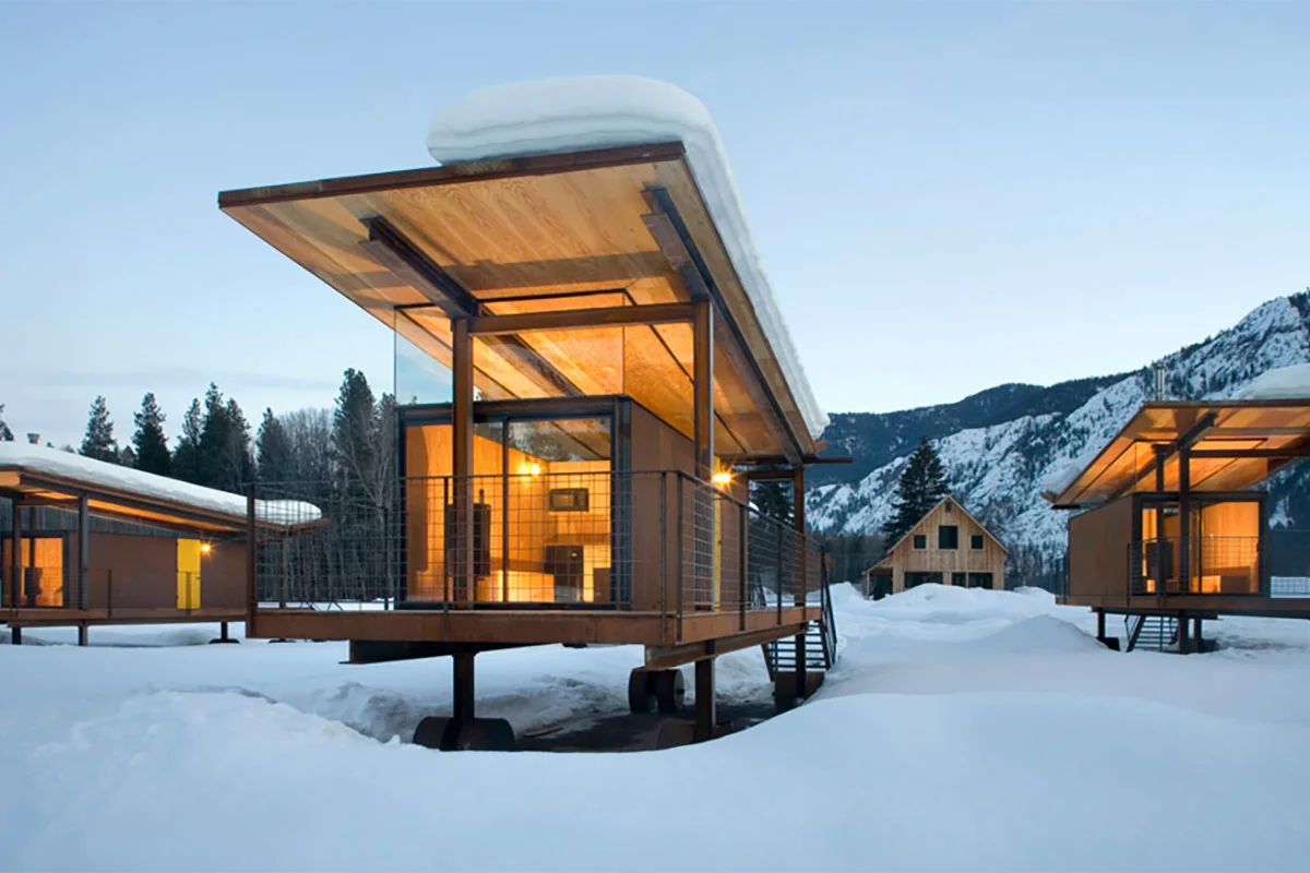 Modern designer rolling huts on wheels in a grassy field with mountains in the background.