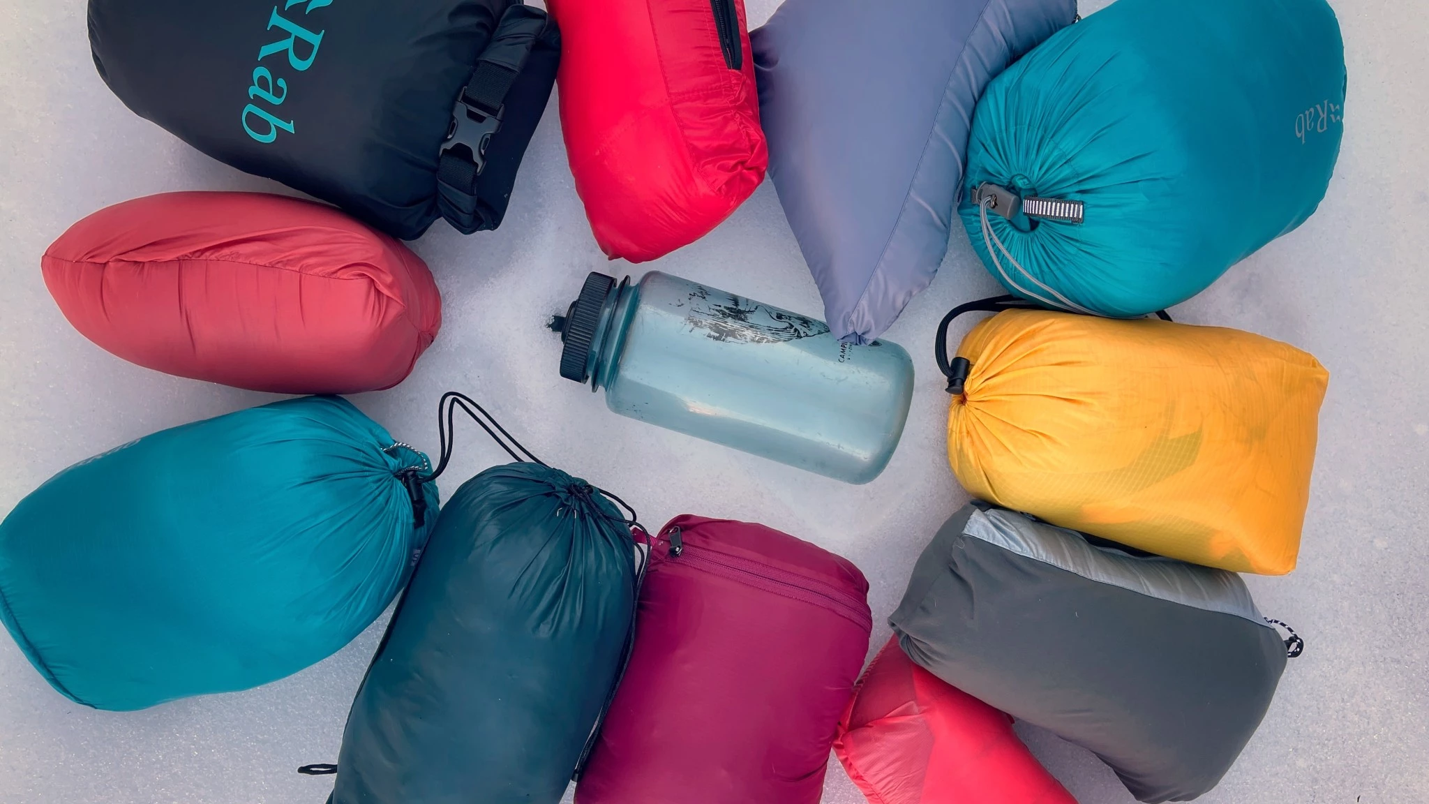 A hand compressing two different insulated jackets to show their packed size.