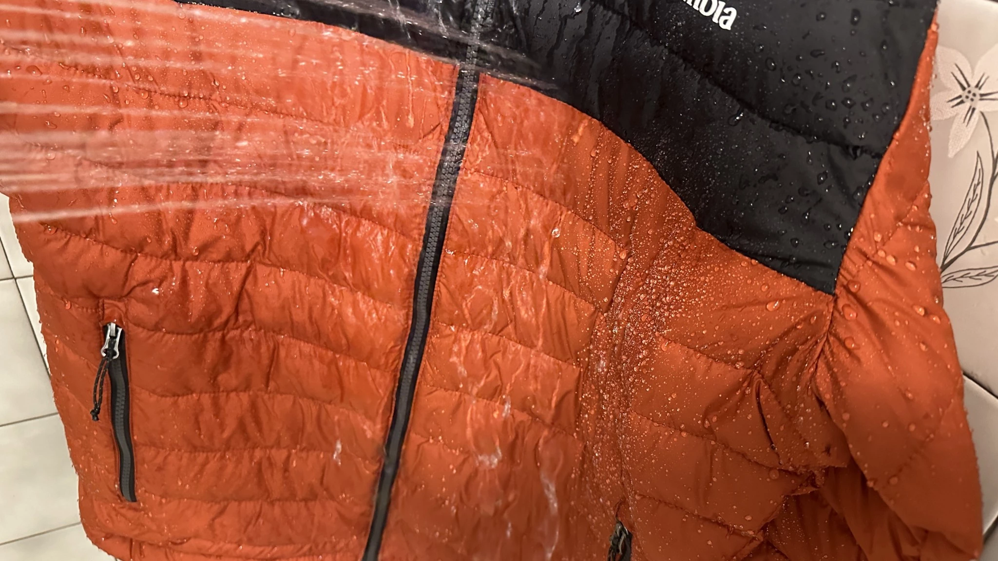 An insulated jacket being sprayed with water to test its moisture resistance.
