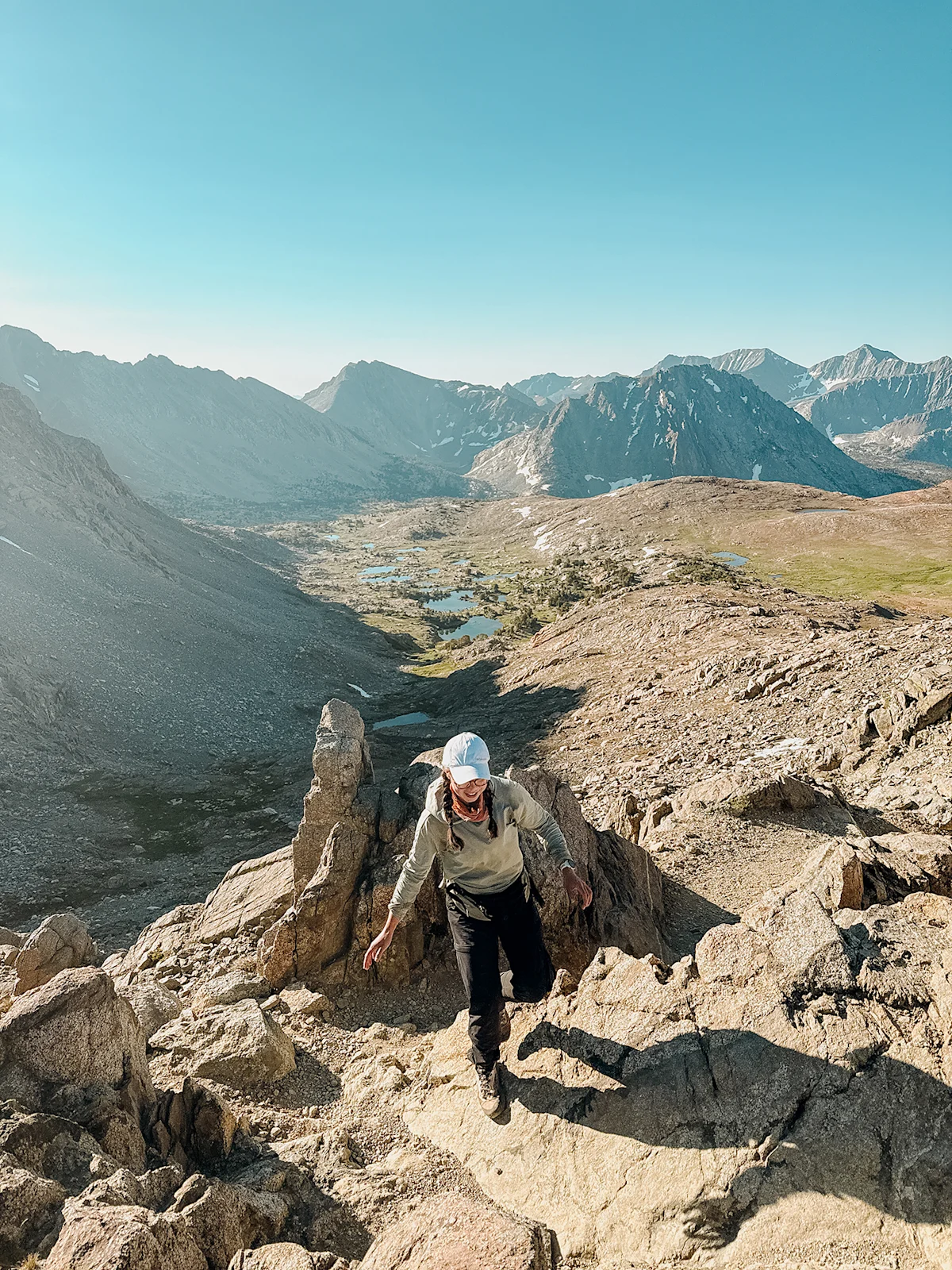 A hiker standing on a vista overlooking a valley wearing trail running shoes.
