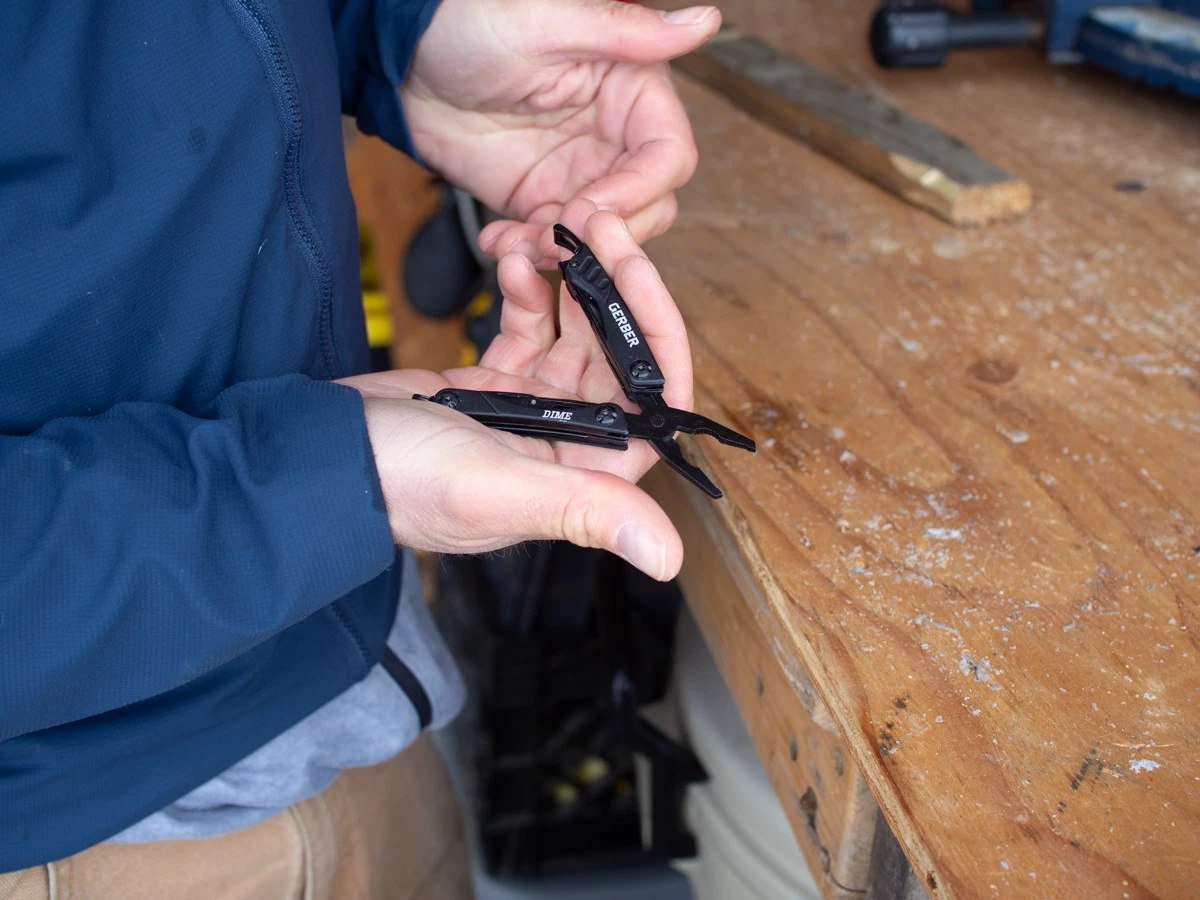 Close-up of the small pliers on a Gerber Dime being used for a precise task.