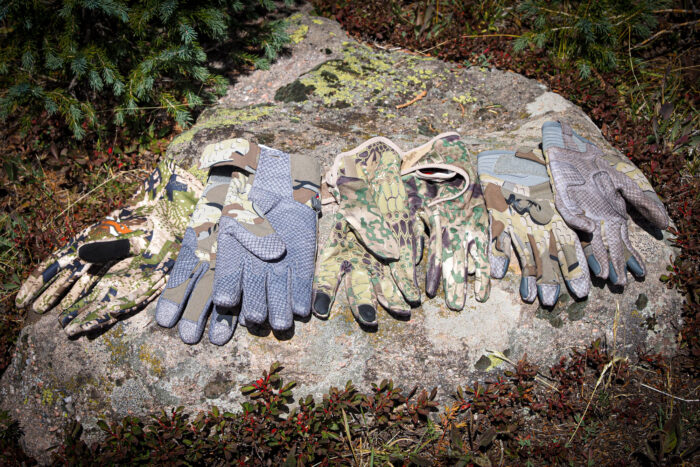 A collection of various hunting gloves used during a 2023 field test in the wilderness.
