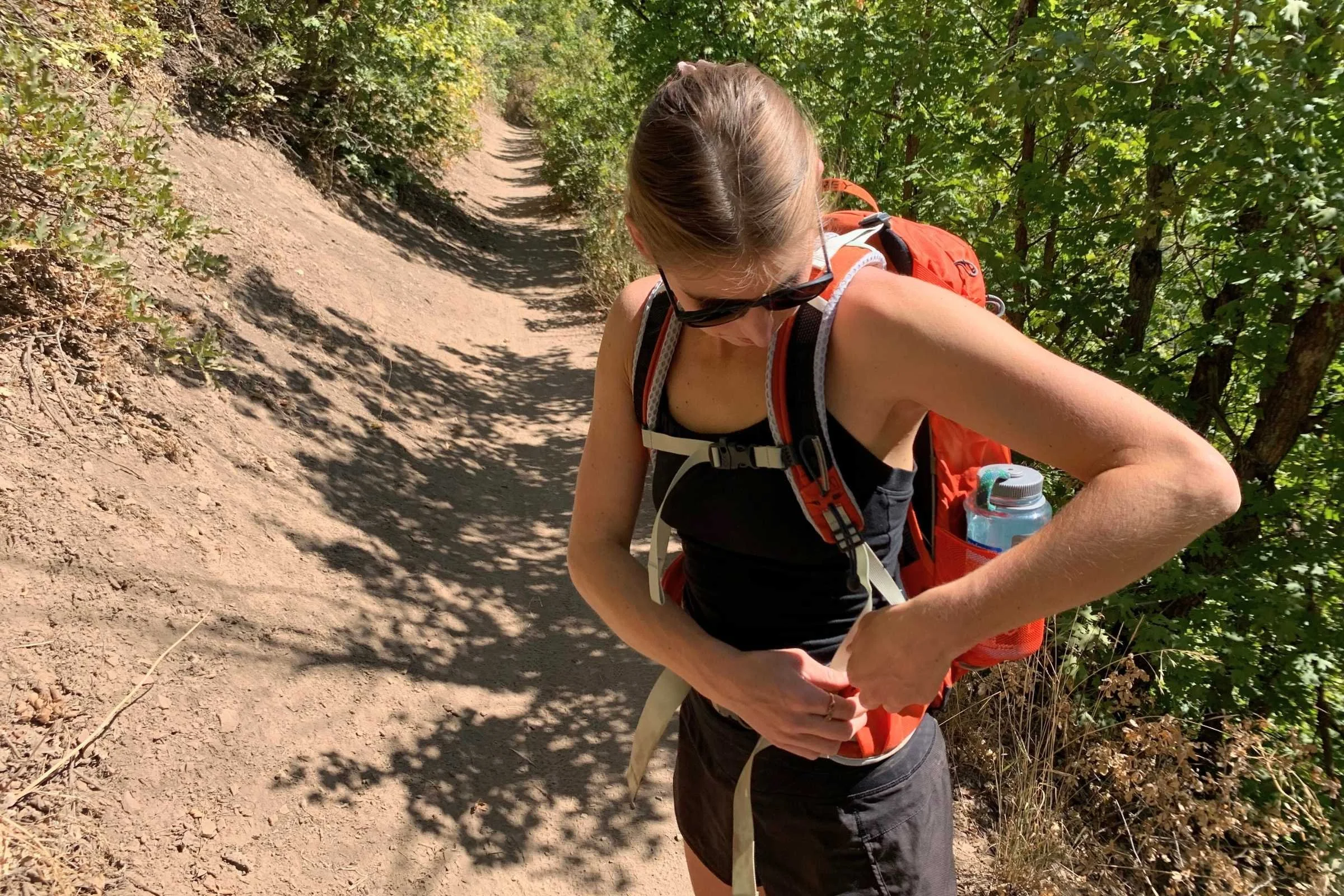 A close-up shot of a hiker's waist showing the padded hip belt of a technical daypack.