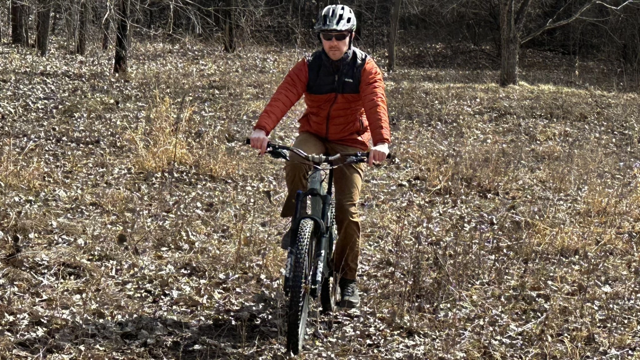 A person hiking at a fast pace wearing a thin, breathable insulated jacket.