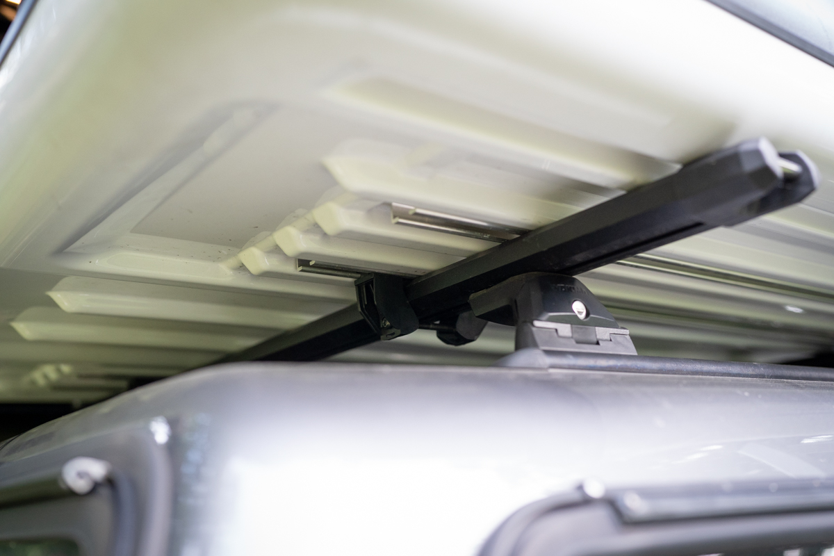 Detailed view of the mounting brackets and hardware connecting a James Baroud Odyssey tent to a roof rack.