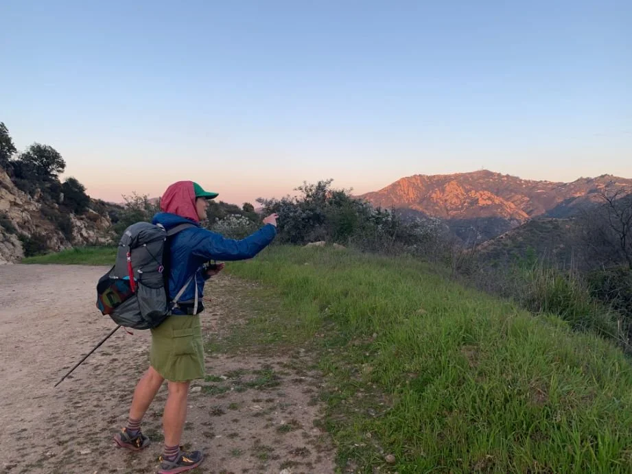 A hiker wearing an insulated jacket while hiking on a windy ridge.
