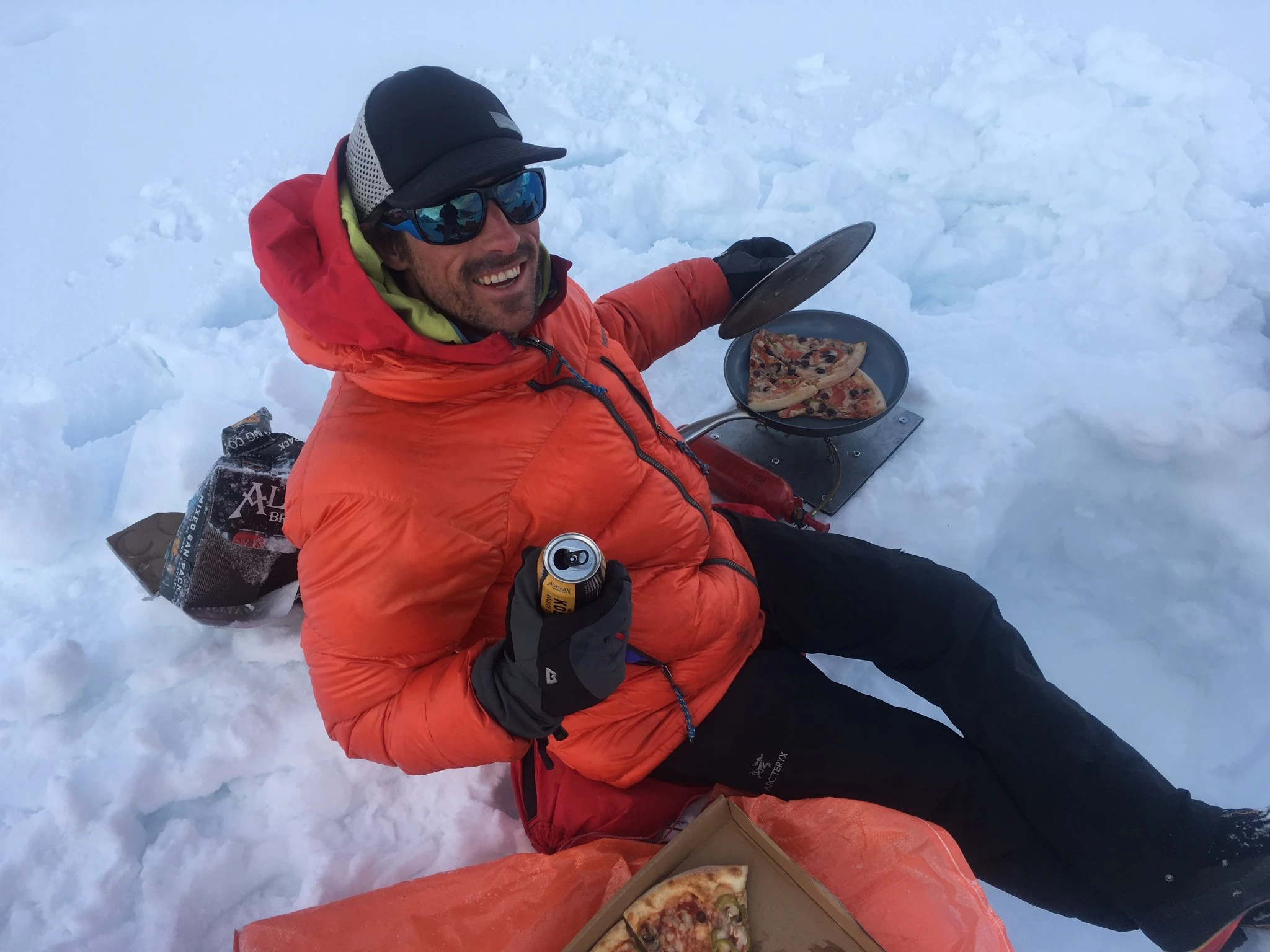 An MSR liquid fuel stove being used on a glacier to reheat food in a large pot.