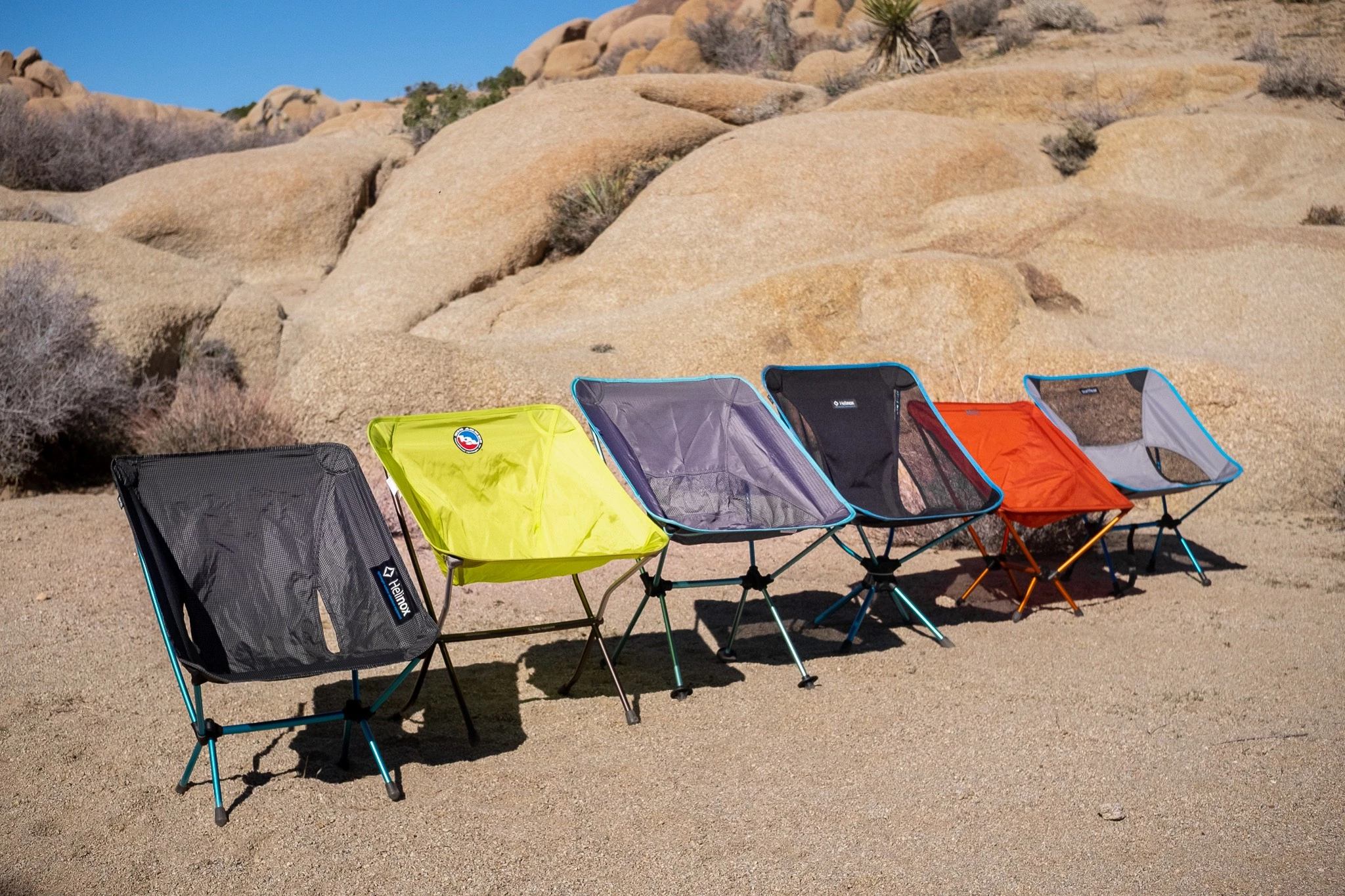 A lineup of several tent-style backpacking chairs showing their aluminum frames and fabric seats.