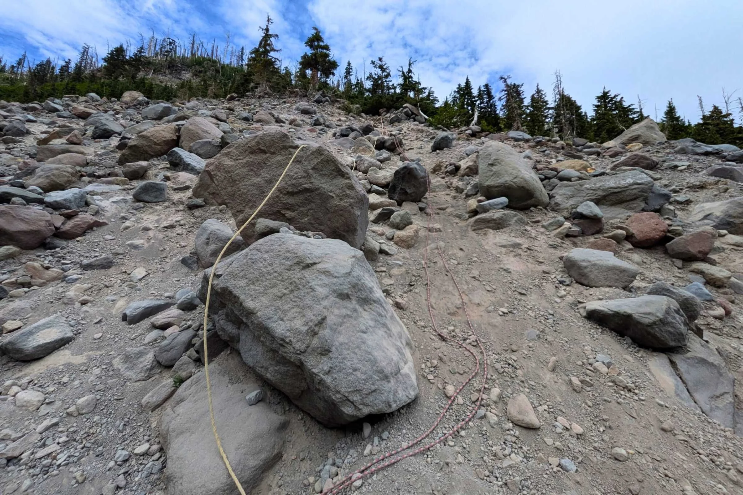 A close-up of a safety rope secured across a rocky, silty river crossing at Elliot Branch.