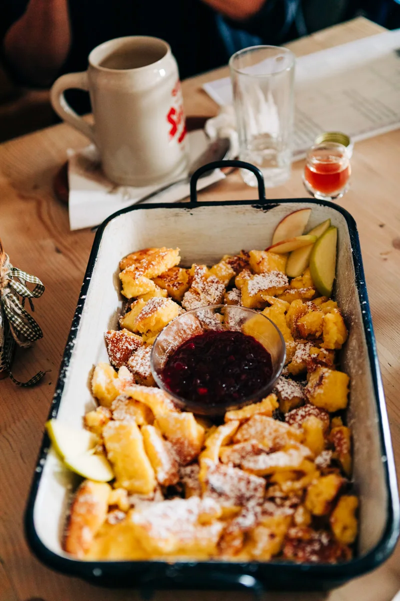 A plate of Kaiserschmarren served on a wooden table at a Salzburg mountain hut.