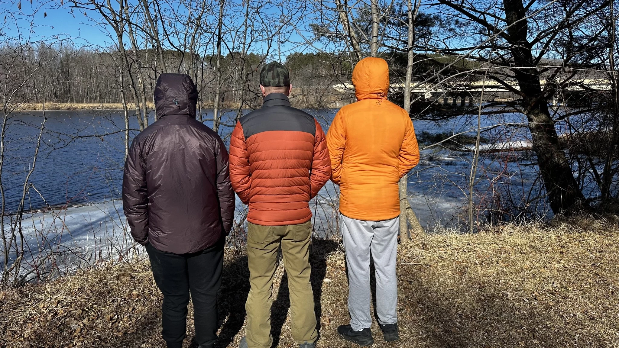A man demonstrating the fit of a mid-layer insulated jacket over other clothing.