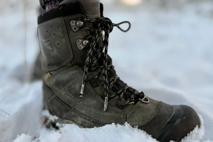 Side profile of the KEEN Revel IV Polar High boot deep in the snow.