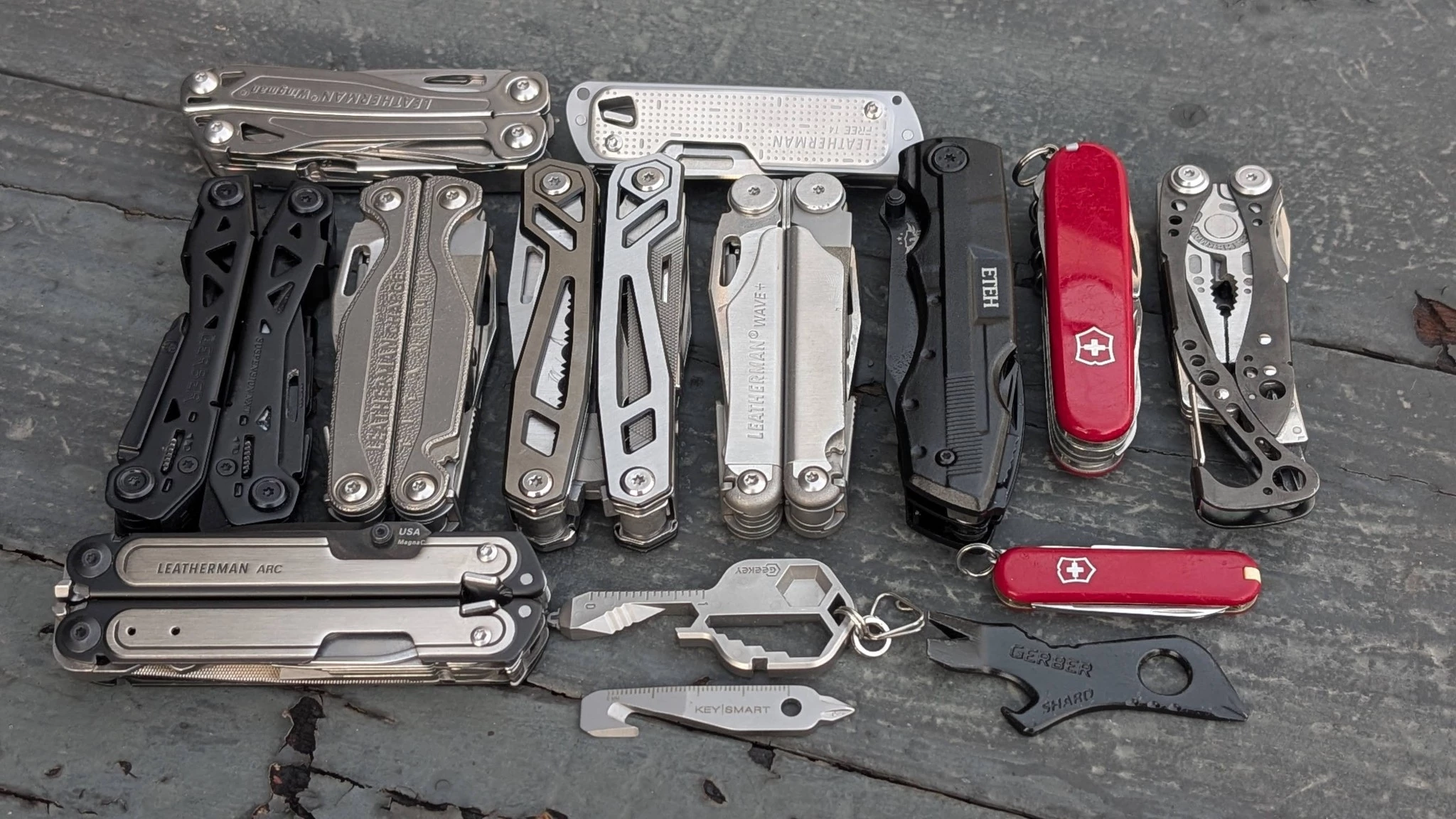 An array of diverse multi-tools from different brands arranged on a flat surface.
