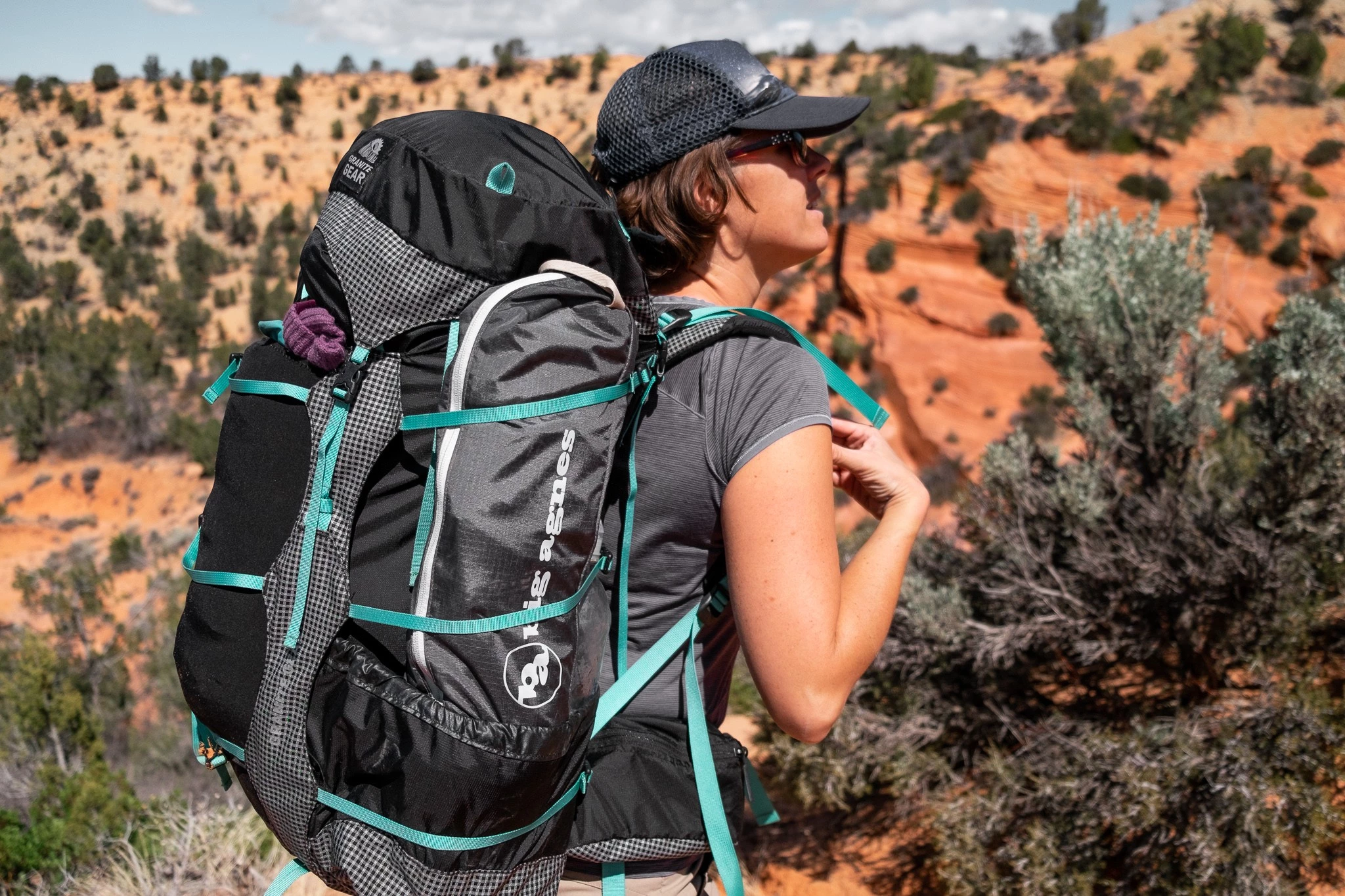 A folded backpacking chair tucked into the side mesh pocket of a hiking pack.