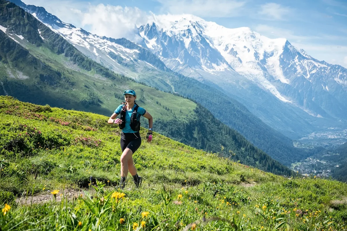 A trail runner navigating a technical ridge line with the Mont Blanc massif in the background.