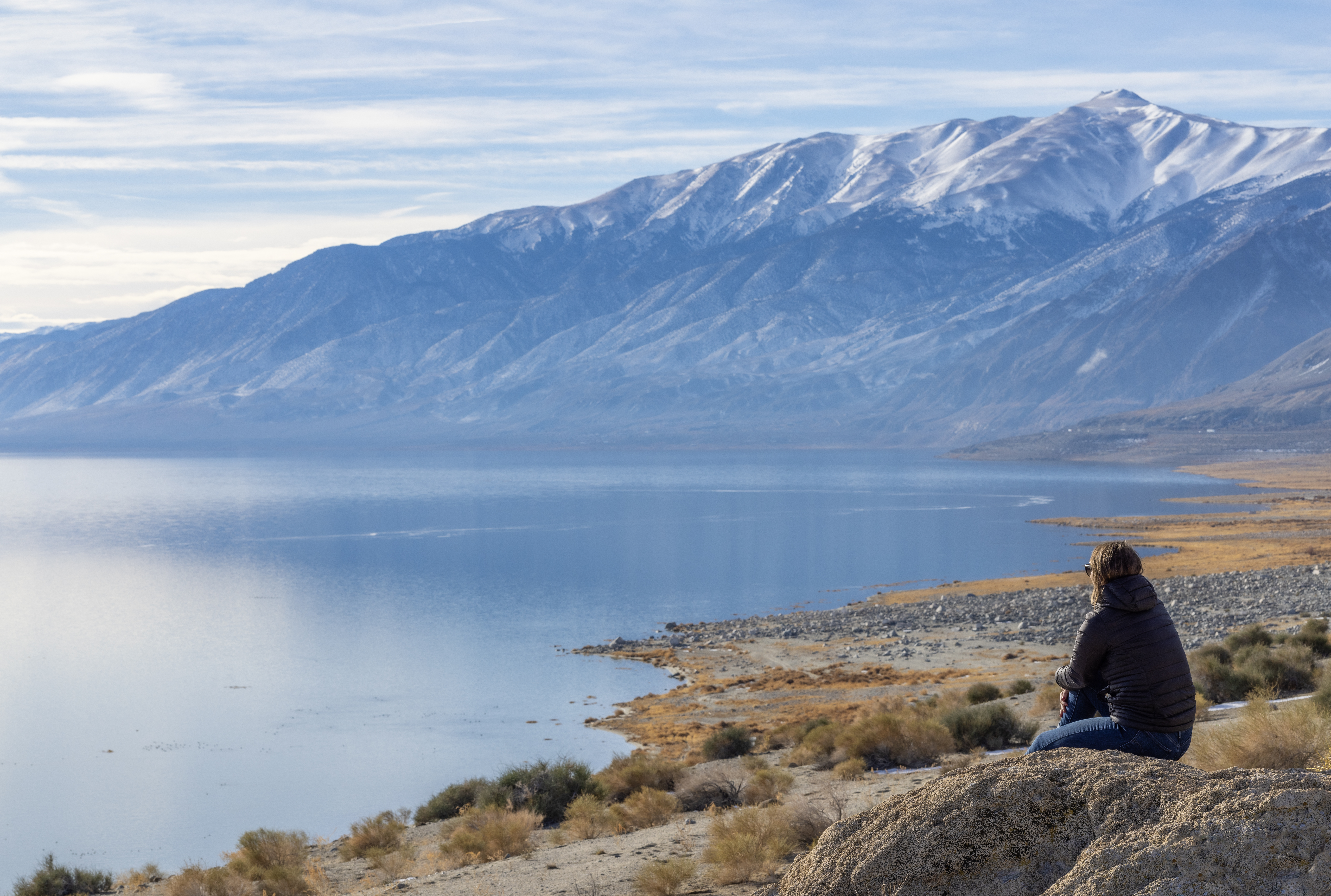 A person sits peacefully on the shore of Walker Lake during the calm early morning hours.