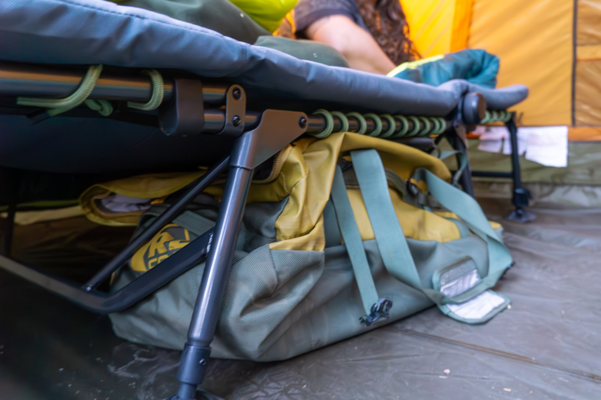 The Wonderland Comfort Cot inside a camping tent with a gear bag stored in the space underneath it.
