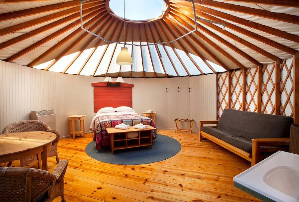Interior of a yurt at Treebones Resort showing a comfortable bed and wood-lattice walls.