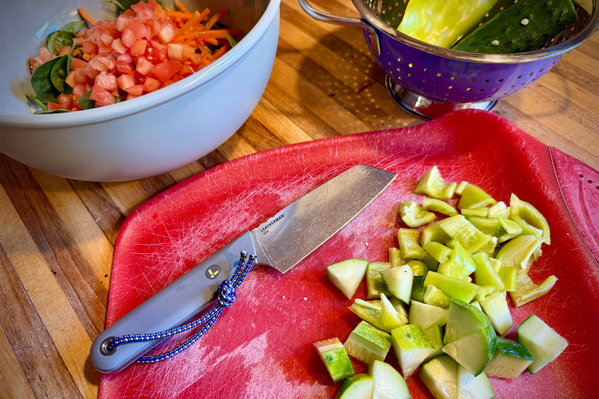Leatherman Rustle on a red cutting board next to finely diced peppers.
