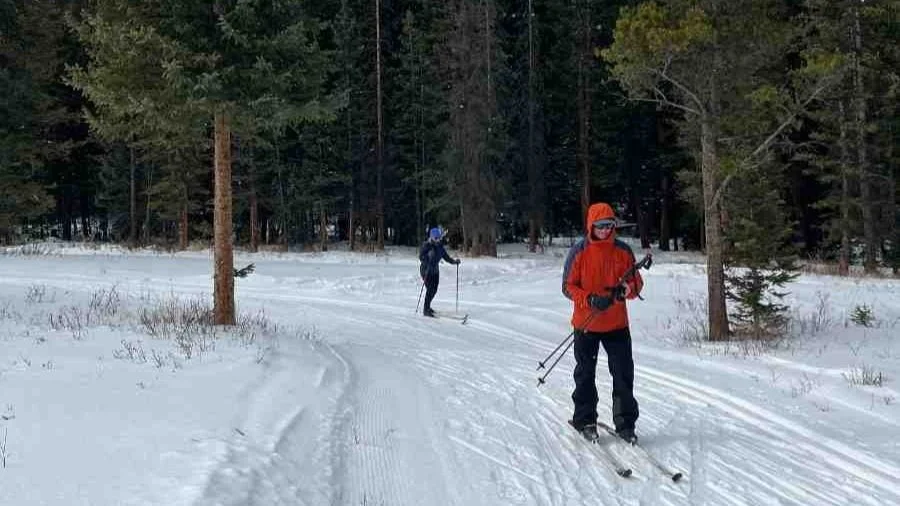 A person stepping into a cross country ski binding on a bright winter day.
