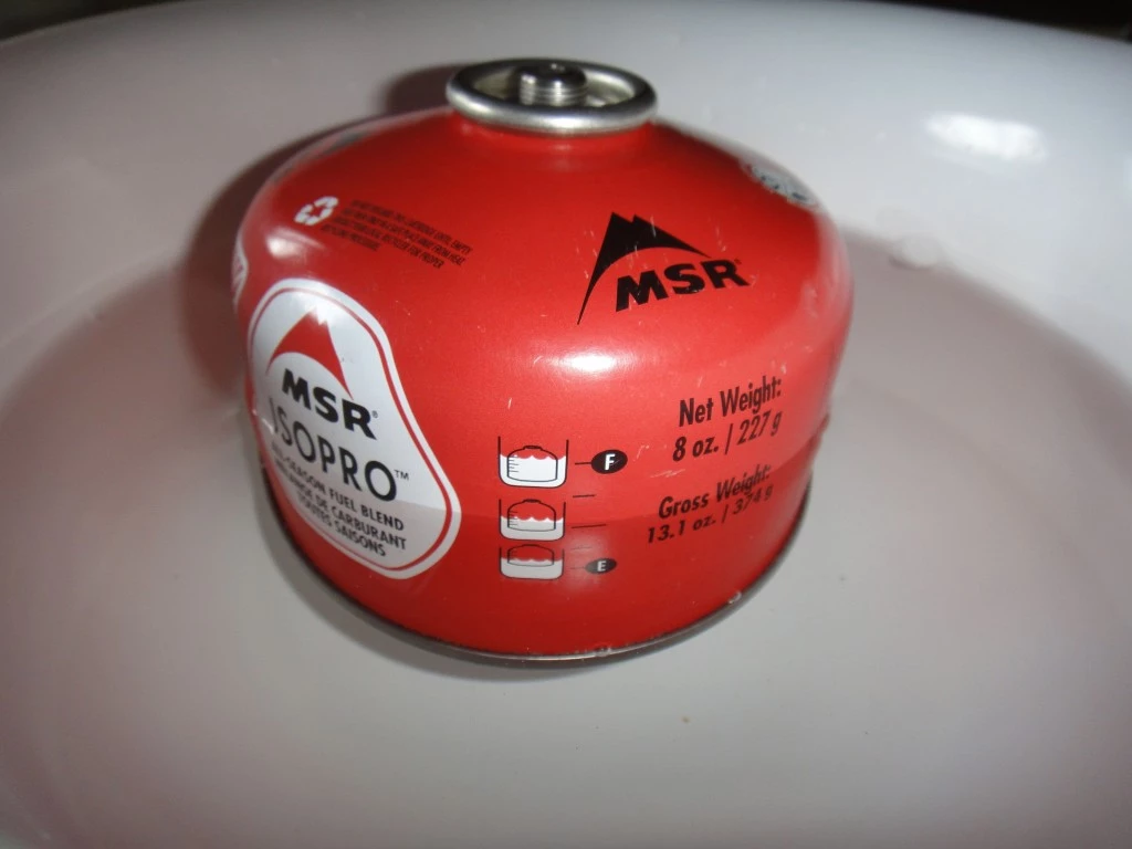 An isobutane fuel canister floating in water to demonstrate how to check its remaining fuel level.