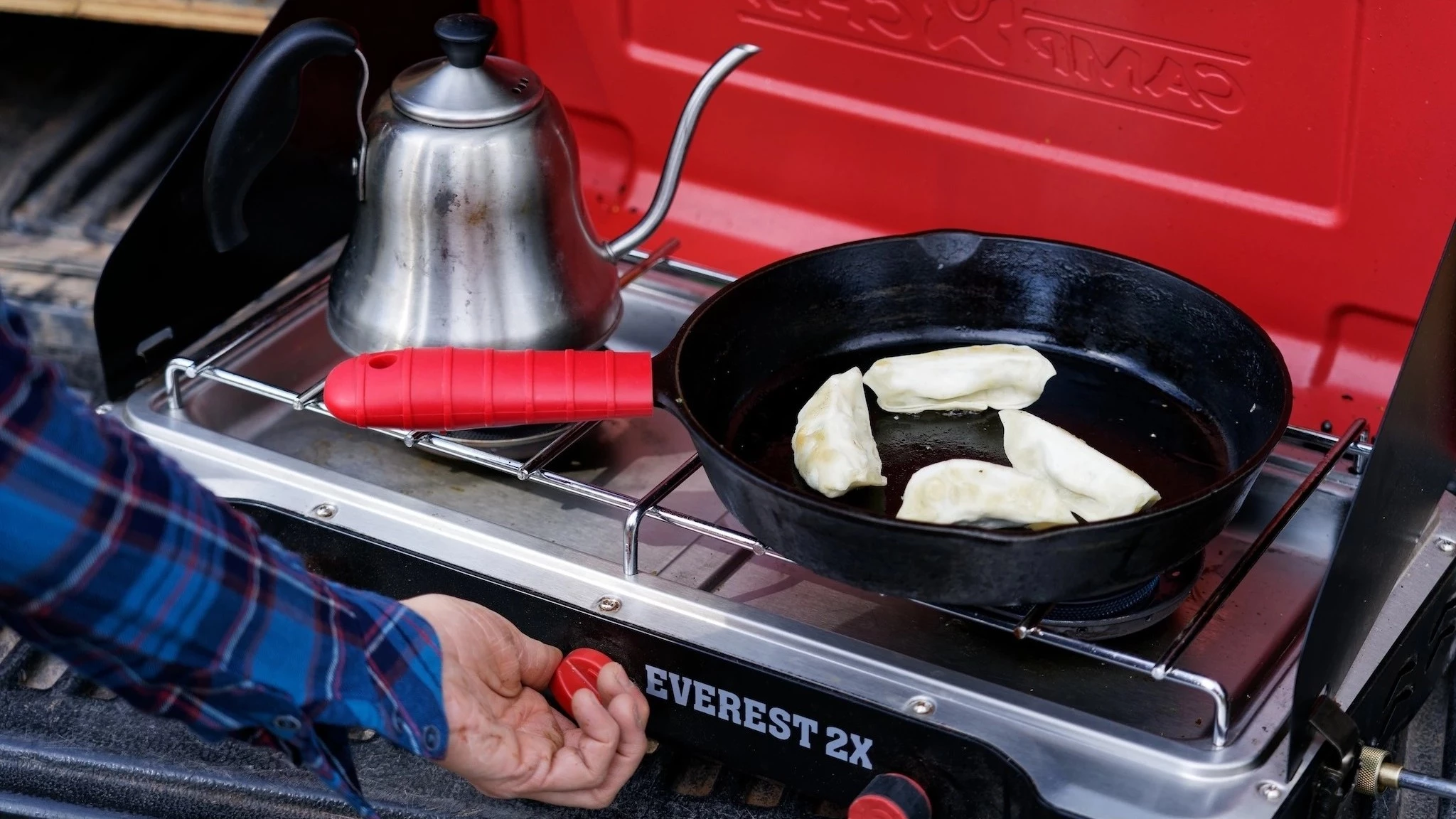 Close-up of a hand pressing a piezo piezoelectric ignition button on a camping stove.