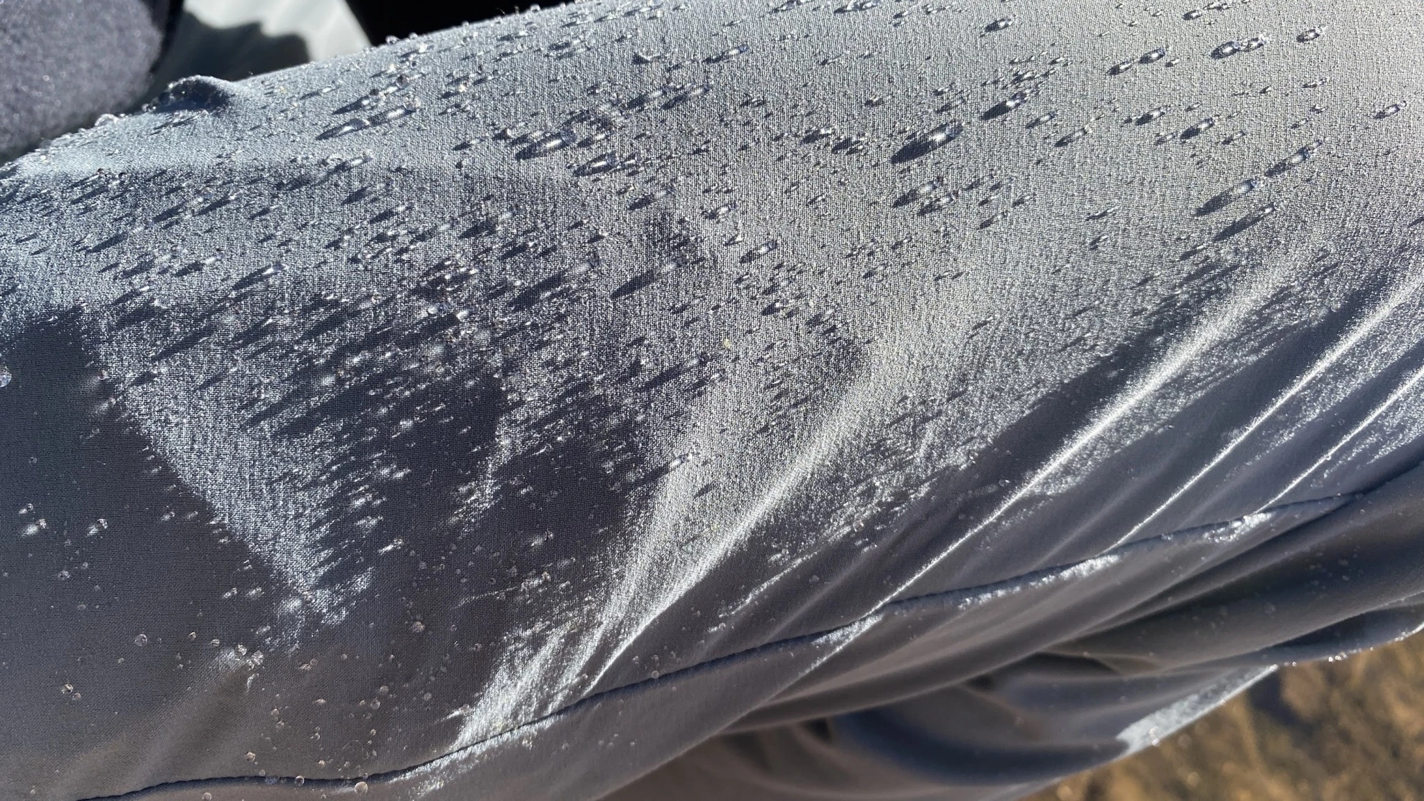 Water droplets beading up and rolling off the surface of water-resistant hiking pants.