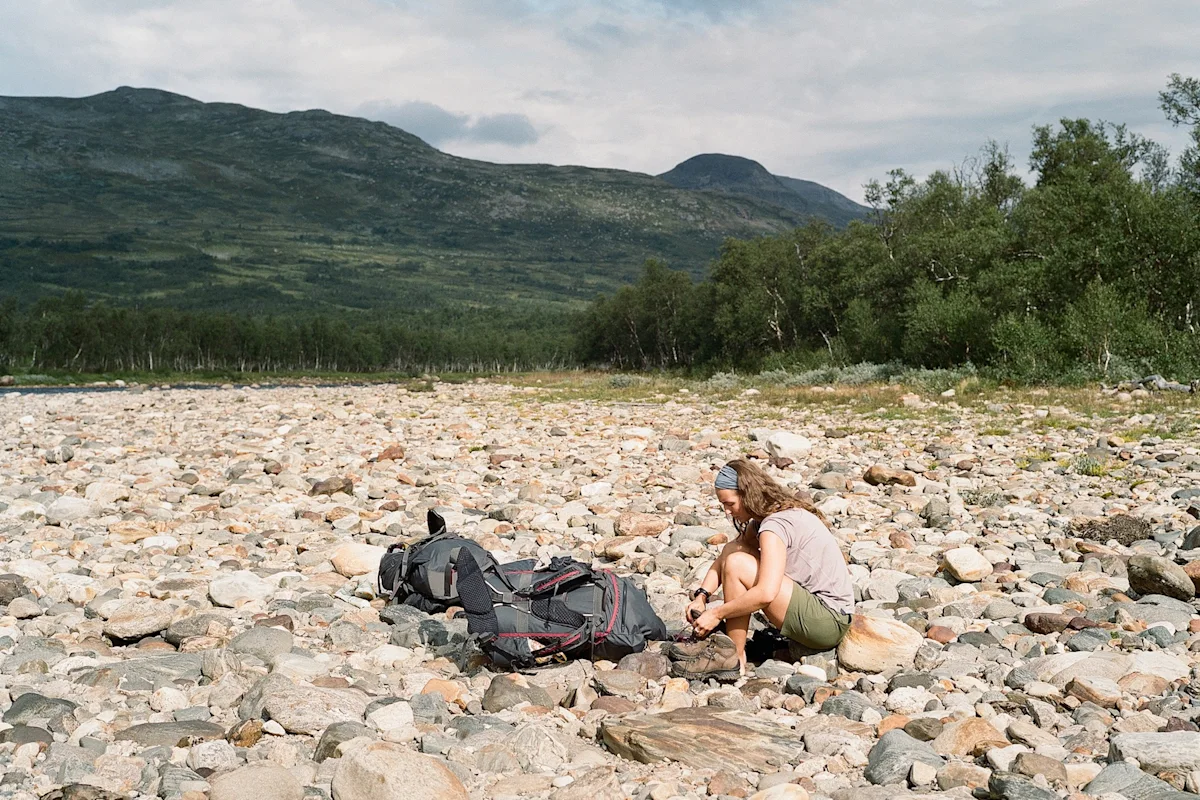A hiker putting on hiking boots on the mountain trail.