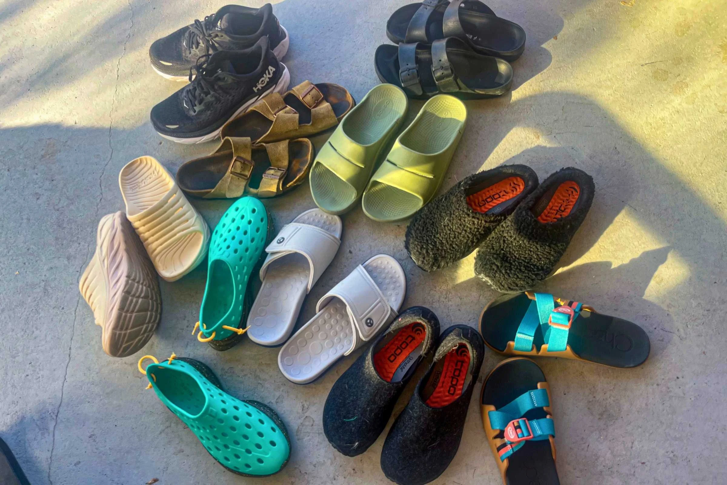 A collection of various recovery slides and sandals gathered for testing.