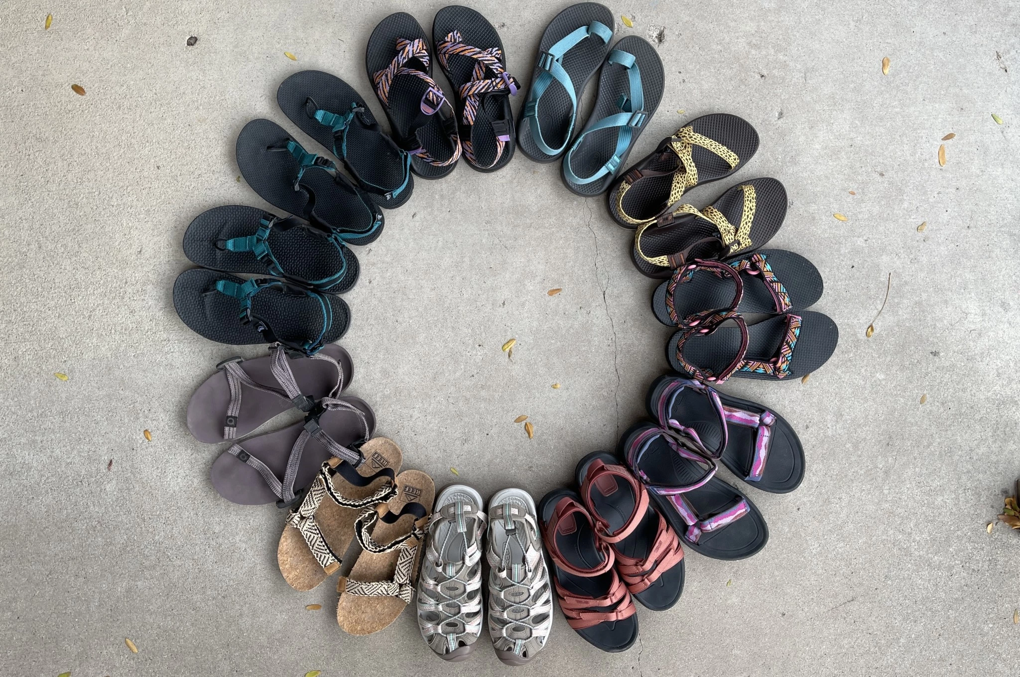 A collection of various colorful sandals tested for the review, including hiking and casual styles.