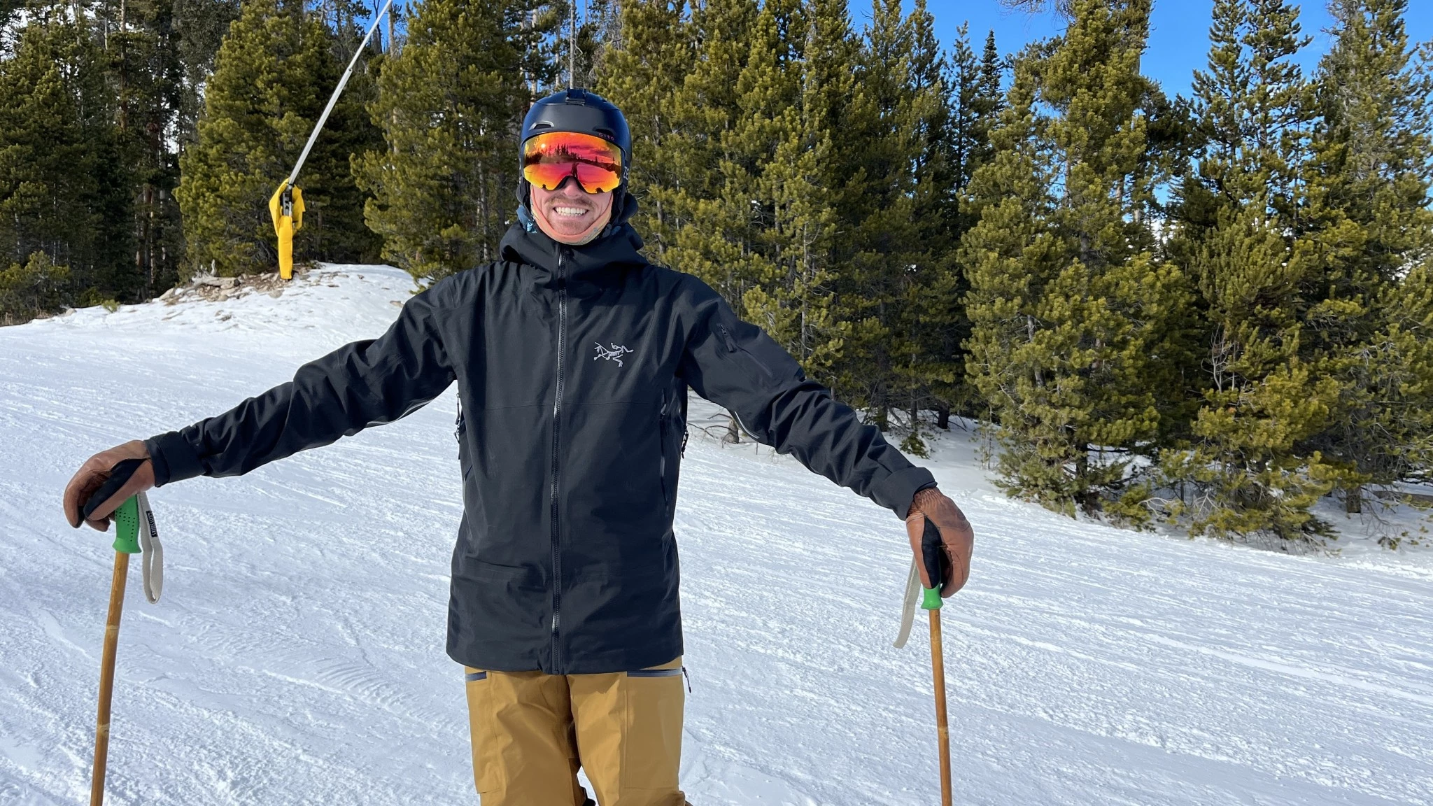 Skier posing in a black Arc'teryx Sabre jacket on a snowy slope.