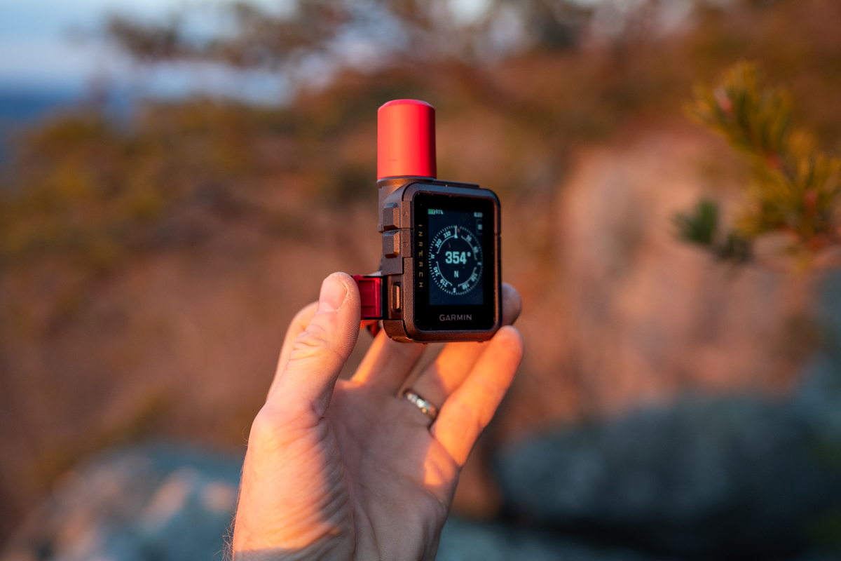 A macro shot of the Garmin inReach Mini 3 showing the protected SOS button and its safety cover.
