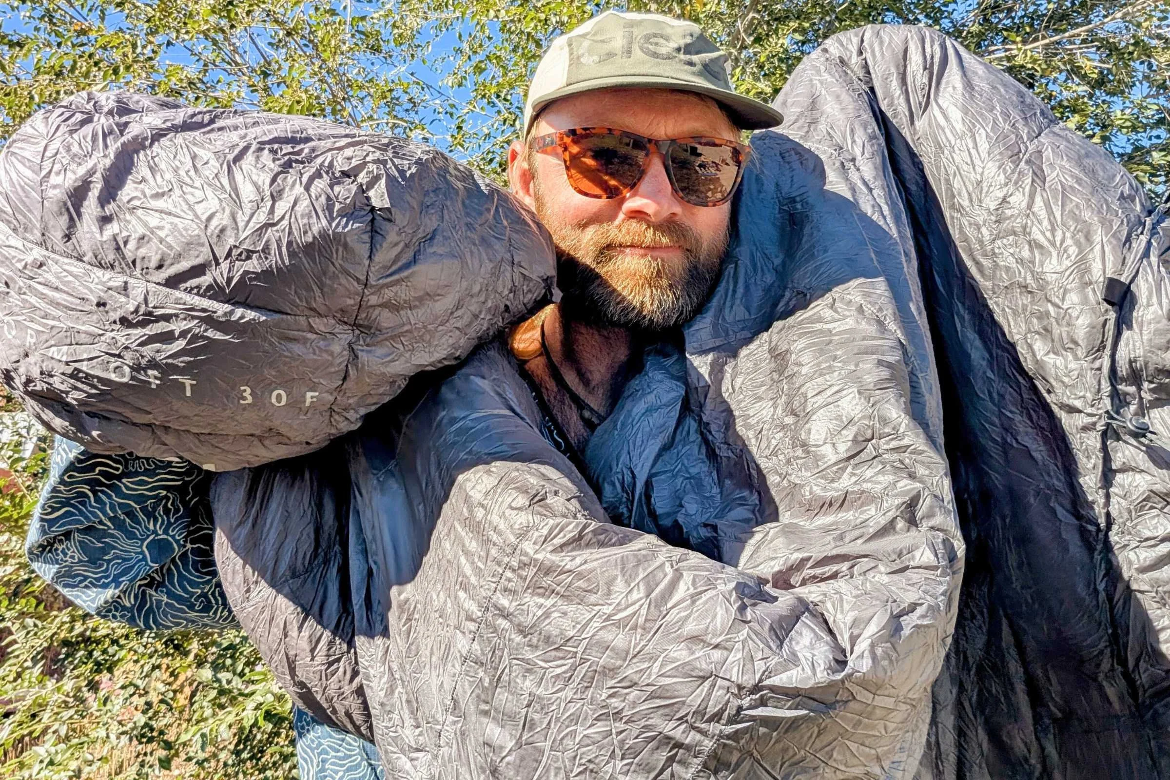 A hiker wearing a lightweight sun hoody and an IPX5-rated power bank charging a GPS device in hand.
