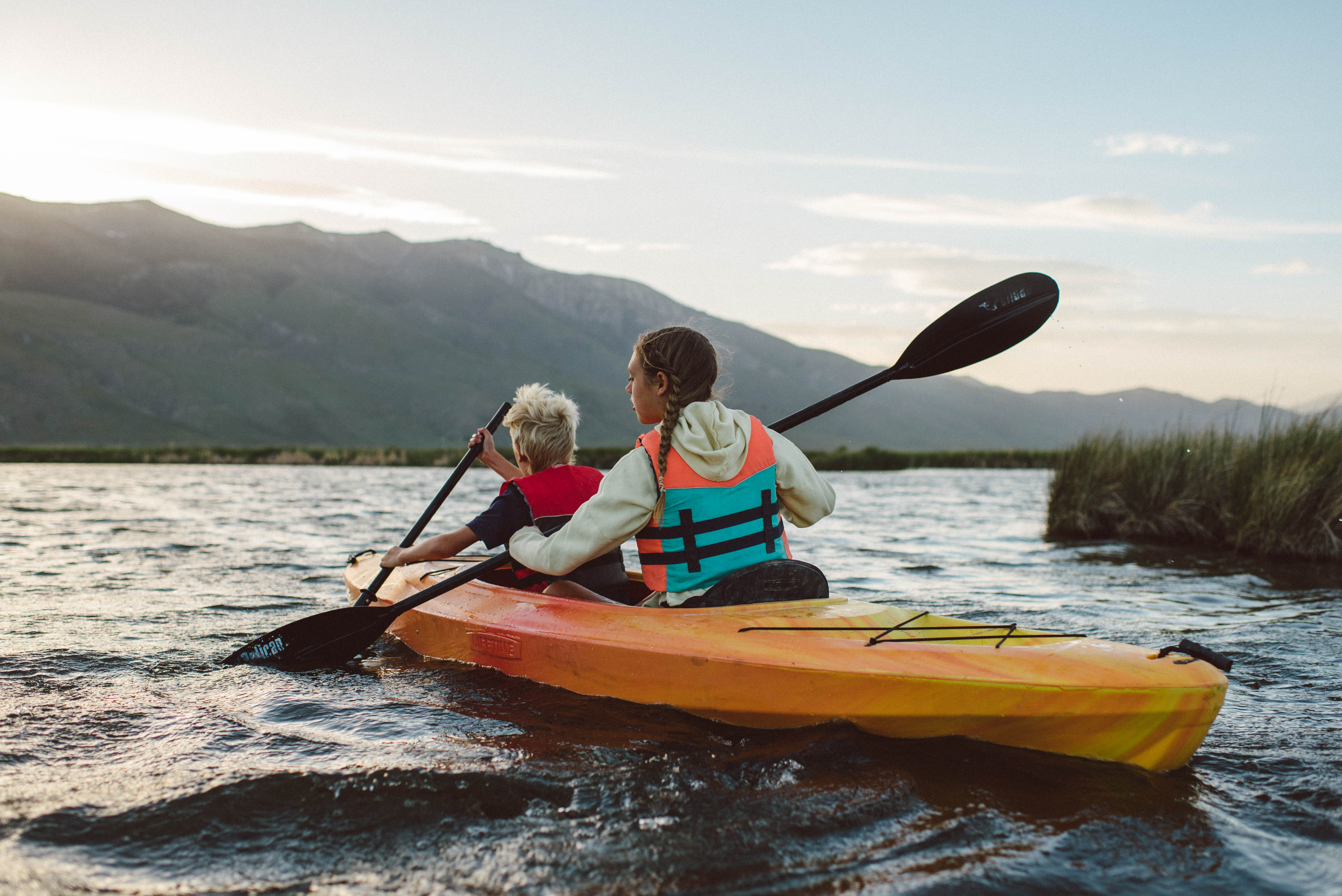 Two young children paddle a double kayak through the reeds at Ruby Lake National Wildlife Refuge.