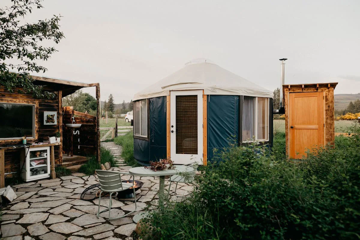 A white canvas glamping tent nestled in the green pastures of Thiselle Creek Farm.