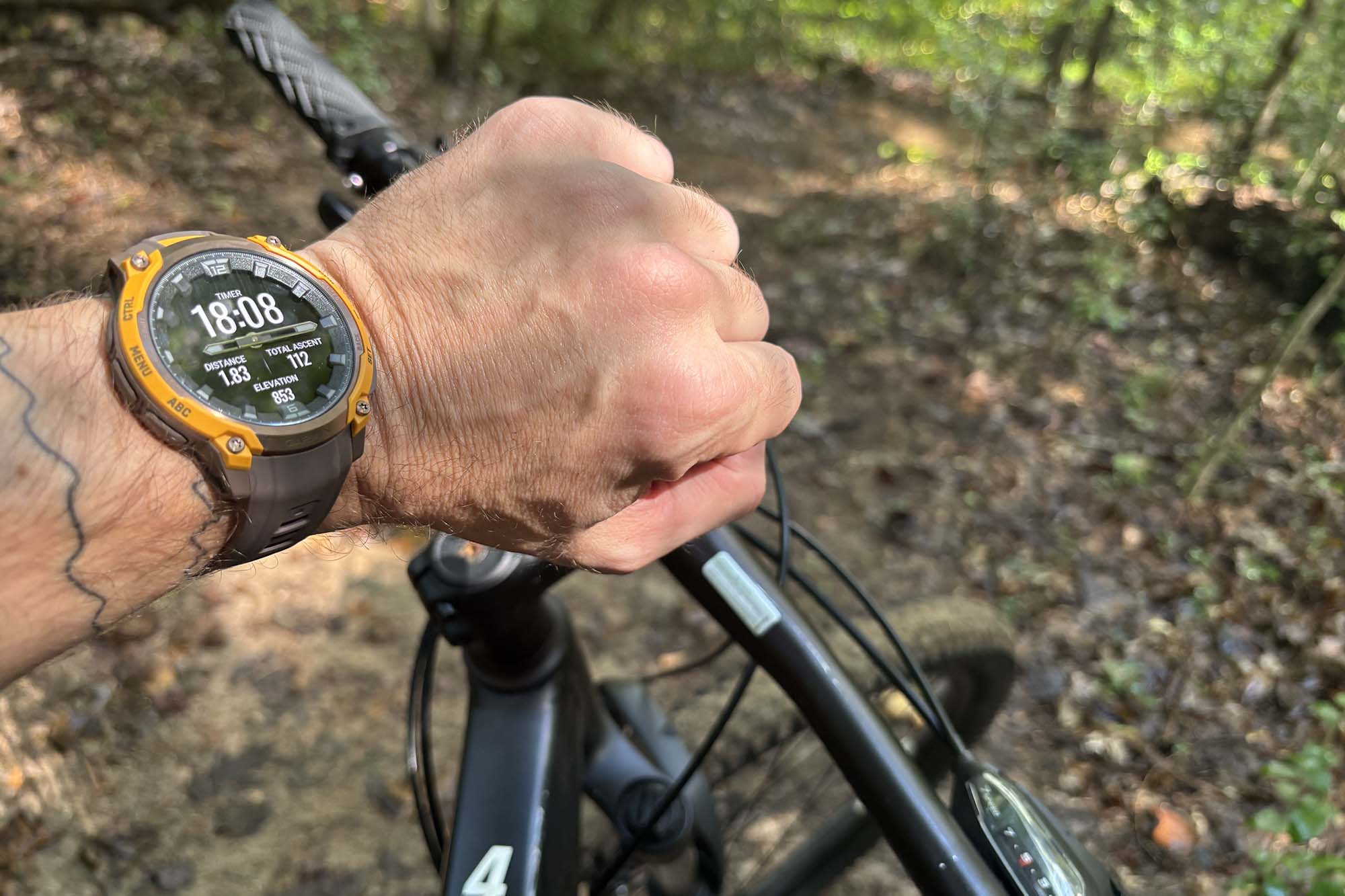 The Garmin Instinct Crossover AMOLED mounted on a cyclist's wrist during a mountain bike ride.
