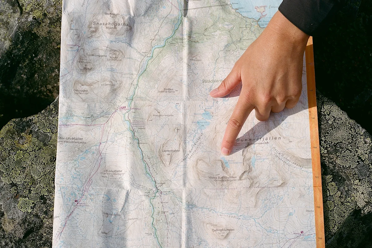 A hiker pointing at a mountain map while out on the trail.
