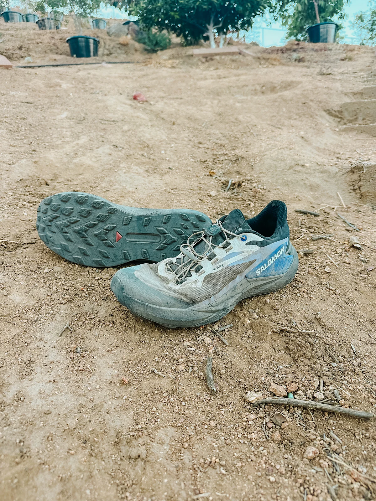 Close-up view of a used trail running shoe outsole showing tread wear and mud.