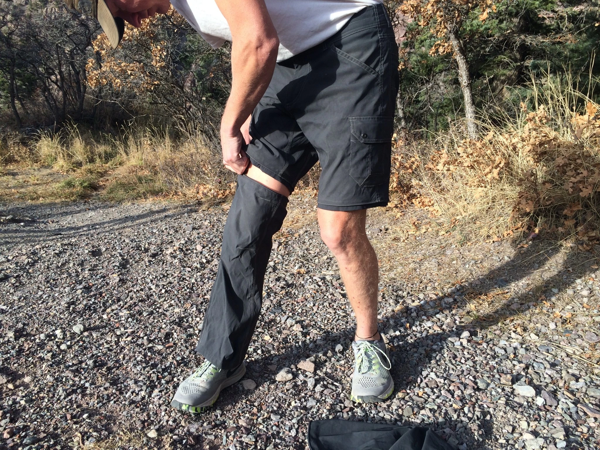 A close-up of a person unzipping the lower leg portion of convertible hiking pants.