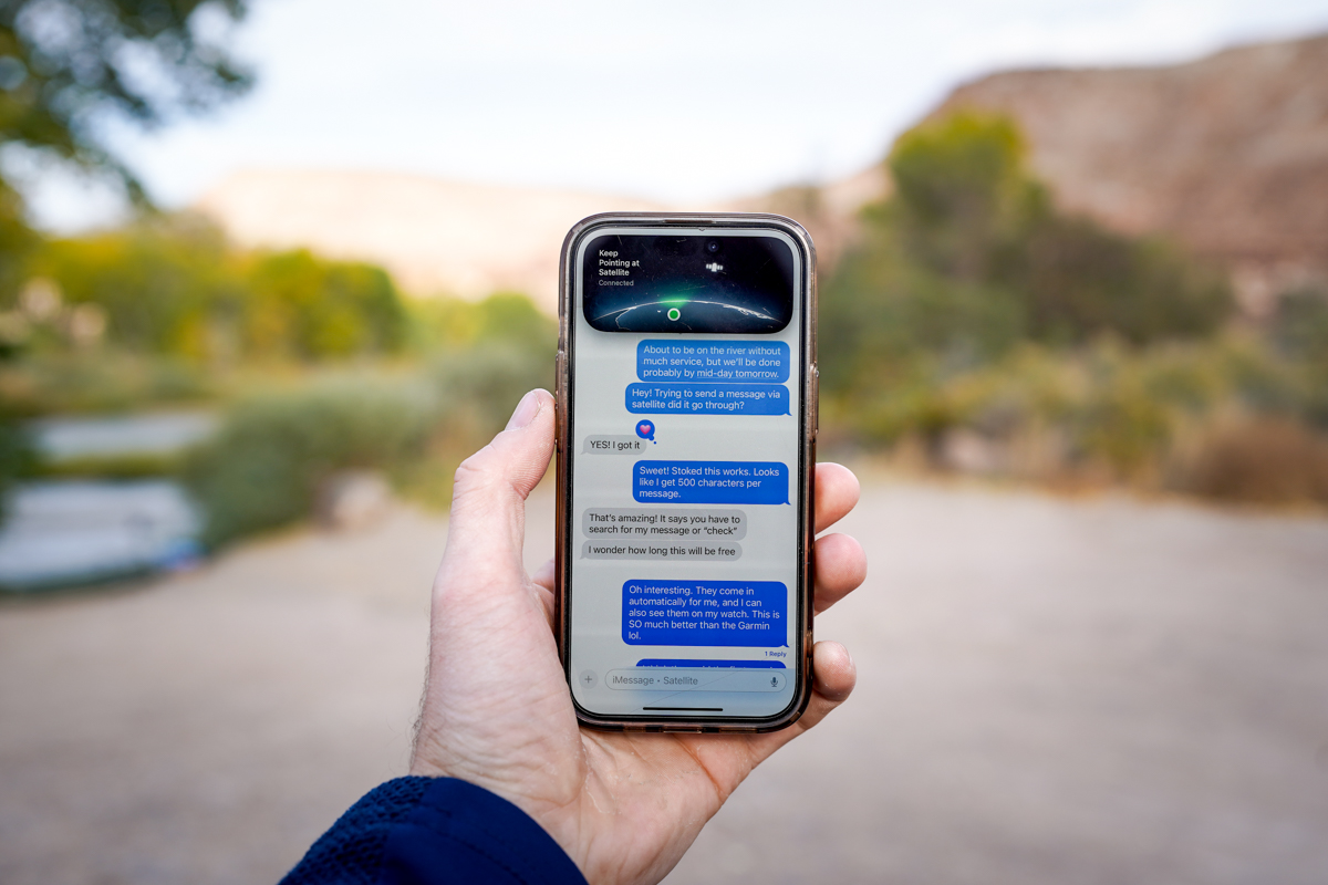 A close-up of a person holding an iPhone displaying the satellite messaging connection screen.