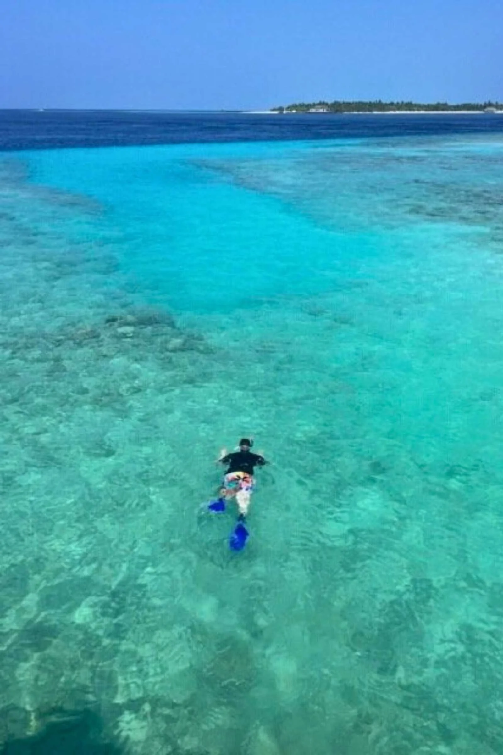 Two people wearing sun protective shirts and hats while snorkeling.