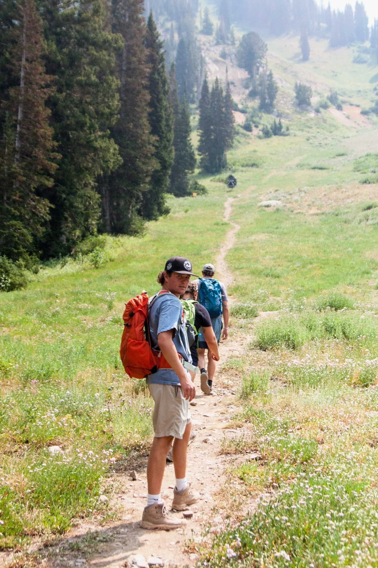 A hiker wearing an Osprey Stratos daypack while trekking through a rocky hiking trail.