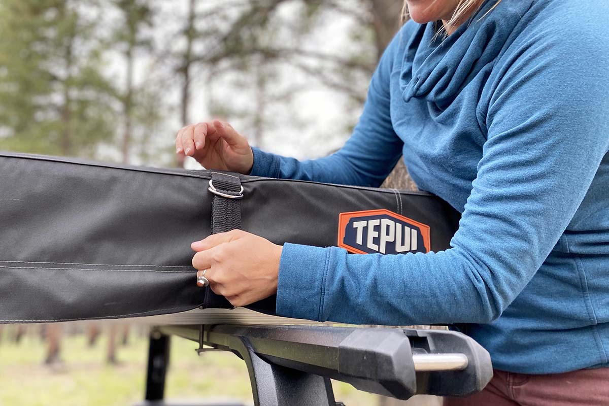 A compact car with a Thule Low-Pro 2 rooftop tent mounted on its roof rack.