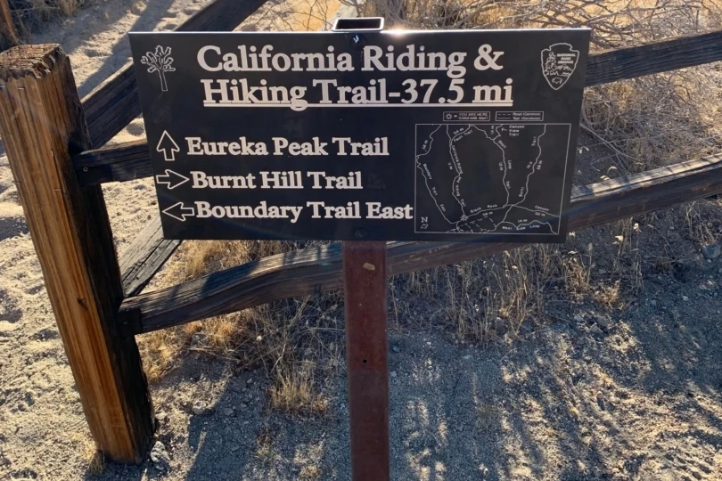 A wooden California Riding and Hiking Trail marker sign standing in the desert.