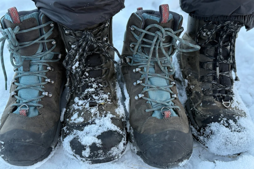 Two pairs of KEEN Revel IV Polar boots covered in snow side by side.