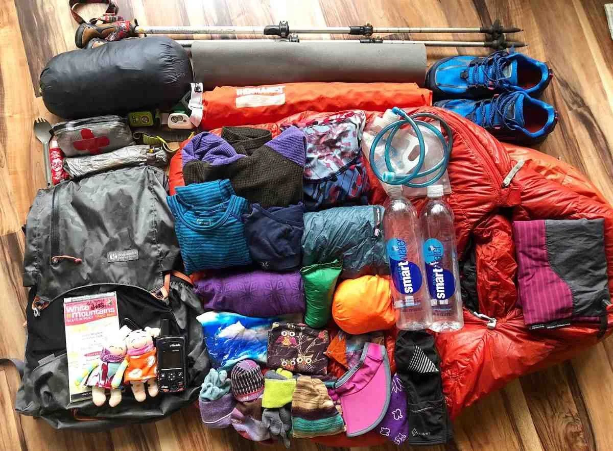 A complete gear layout for summer hiking including clothing, pack, and safety essentials.